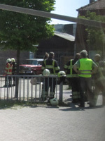 Meester Theo (in het gele hesje) spreekt met de brandweermannen, achter hen is de loods te zien